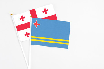 Aruba and Georgia stick flags on white background. High quality fabric, miniature national flag. Peaceful global concept.White floor for copy space.