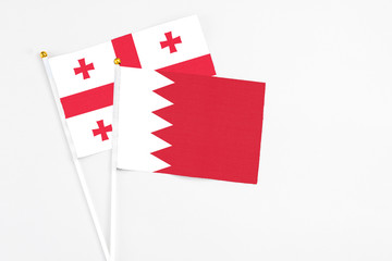 Bahrain and Georgia stick flags on white background. High quality fabric, miniature national flag. Peaceful global concept.White floor for copy space.