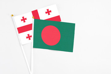 Bangladesh and Georgia stick flags on white background. High quality fabric, miniature national flag. Peaceful global concept.White floor for copy space.