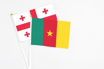 Cameroon and Georgia stick flags on white background. High quality fabric, miniature national flag. Peaceful global concept.White floor for copy space.