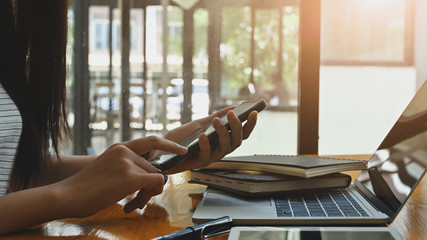 Sideview close-up smartphone on female hands.