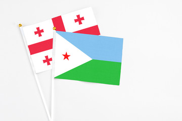 Djibouti and Georgia stick flags on white background. High quality fabric, miniature national flag. Peaceful global concept.White floor for copy space.