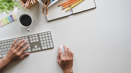Male hands working on computer on white copy space office desk background.