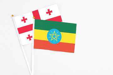 Ethiopia and Georgia stick flags on white background. High quality fabric, miniature national flag. Peaceful global concept.White floor for copy space.