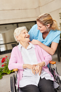 Glückliche Seniorin im Rollstuhl mit Pflegekraft