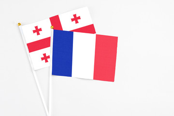 France and Georgia stick flags on white background. High quality fabric, miniature national flag. Peaceful global concept.White floor for copy space.