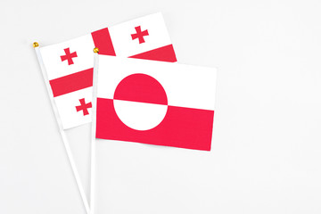Greenland and Georgia stick flags on white background. High quality fabric, miniature national flag. Peaceful global concept.White floor for copy space.