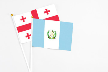 Guatemala and Georgia stick flags on white background. High quality fabric, miniature national flag. Peaceful global concept.White floor for copy space.
