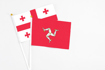 Isle Of Man and Georgia stick flags on white background. High quality fabric, miniature national flag. Peaceful global concept.White floor for copy space.