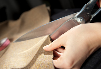 a tailor is cutting the fabric with scissors