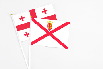 Jersey and Georgia stick flags on white background. High quality fabric, miniature national flag. Peaceful global concept.White floor for copy space.