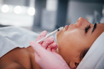 Obraz na płótnie Canvas Close up view of woman that lying down in spa salon and have injection by the syringe into her face skin