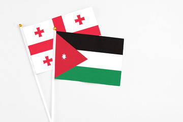 Jordan and Georgia stick flags on white background. High quality fabric, miniature national flag. Peaceful global concept.White floor for copy space.
