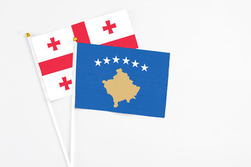 Kosovo and Georgia stick flags on white background. High quality fabric, miniature national flag. Peaceful global concept.White floor for copy space.