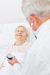 Arzt misst Blutdruck einer kranken Seniorin