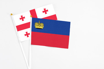 Liechtenstein and Georgia stick flags on white background. High quality fabric, miniature national flag. Peaceful global concept.White floor for copy space.