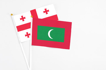 Maldives and Georgia stick flags on white background. High quality fabric, miniature national flag. Peaceful global concept.White floor for copy space.