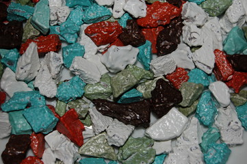 background colored chocolate candies in the shape of stones: red, beige, black, turquoise