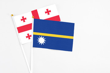 Nauru and Georgia stick flags on white background. High quality fabric, miniature national flag. Peaceful global concept.White floor for copy space.