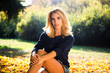 autumn season. portrait of a woman with blue sweater playing with leaves