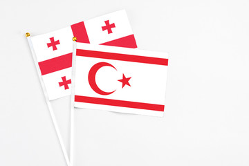 Northern Cyprus and Georgia stick flags on white background. High quality fabric, miniature national flag. Peaceful global concept.White floor for copy space.