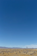 Fototapeta premium Desert landscape with blue sky and wind pump