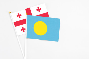 Palau and Georgia stick flags on white background. High quality fabric, miniature national flag. Peaceful global concept.White floor for copy space.