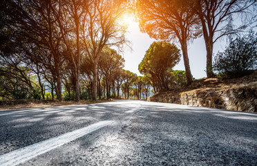 Empty long mountain road to the horizon on a sunny summer day at bright sunset