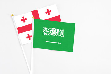Saudi Arabia and Georgia stick flags on white background. High quality fabric, miniature national flag. Peaceful global concept.White floor for copy space.