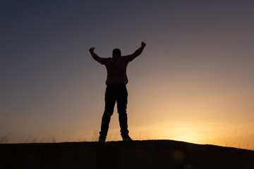 Fototapeta na wymiar silhouette of man raising arms sunset