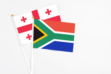 South Africa and Georgia stick flags on white background. High quality fabric, miniature national flag. Peaceful global concept.White floor for copy space.