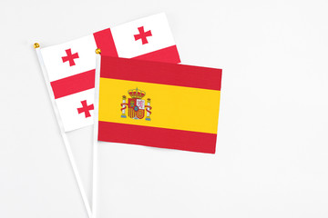 Spain and Georgia stick flags on white background. High quality fabric, miniature national flag. Peaceful global concept.White floor for copy space.