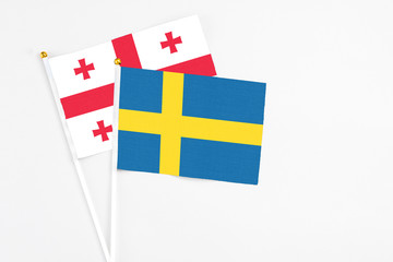 Sweden and Georgia stick flags on white background. High quality fabric, miniature national flag. Peaceful global concept.White floor for copy space.