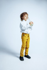 Pretty young boy in casual clothes on white studio background. Fashionable posing. Caucasian male preschooler with bright facial emotions. Childhood, expression, having fun. Drinking milk, enjoying,