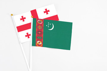 Turkmenistan and Georgia stick flags on white background. High quality fabric, miniature national flag. Peaceful global concept.White floor for copy space.