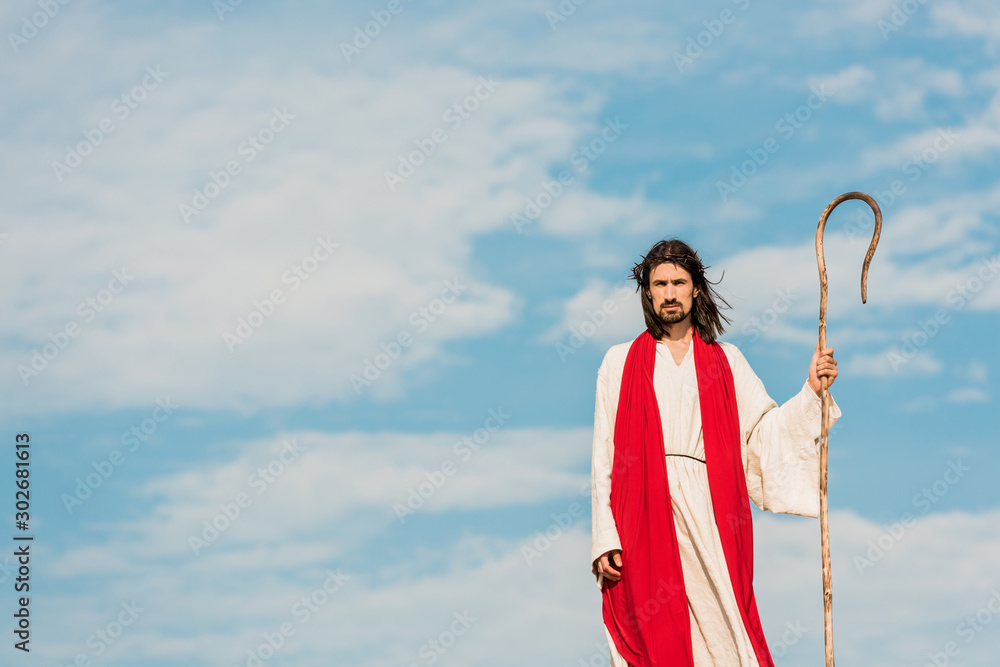 Wall mural handsome bearded man holding wooden cane and standing outside