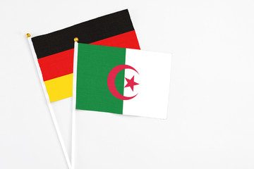 Algeria and Germany stick flags on white background. High quality fabric, miniature national flag. Peaceful global concept.White floor for copy space.