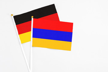 Armenia and Germany stick flags on white background. High quality fabric, miniature national flag. Peaceful global concept.White floor for copy space.