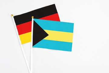 Bahamas and Germany stick flags on white background. High quality fabric, miniature national flag. Peaceful global concept.White floor for copy space.