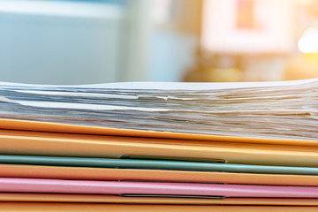 Stack of documents in files on desk in office.