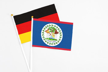 Belize and Germany stick flags on white background. High quality fabric, miniature national flag. Peaceful global concept.White floor for copy space.
