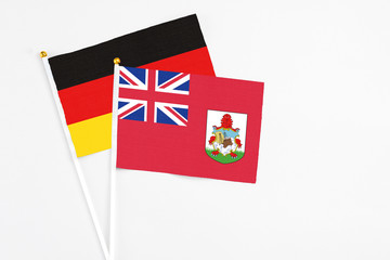Fototapeta premium Bermuda and Germany stick flags on white background. High quality fabric, miniature national flag. Peaceful global concept.White floor for copy space.