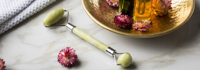 Massage Steinroller mit Naturkosmetik Beauty Öl Serum Flaschen an Handtuch, Gold Metall Schale und...