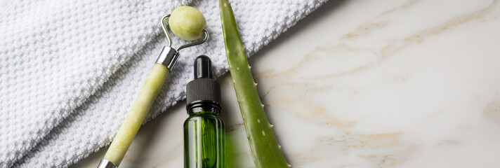 Massage Steinroller, Aloe Vera Blatt und Naturkosmetik Beauty Öl Serum Flasche grün an Handtuch...