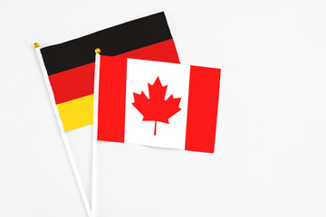 Fototapeta na wymiar Canada and Germany stick flags on white background. High quality fabric, miniature national flag. Peaceful global concept.White floor for copy space.
