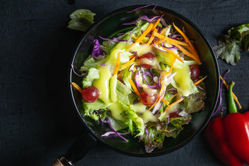 .Bowl of vegetable salad on black background.