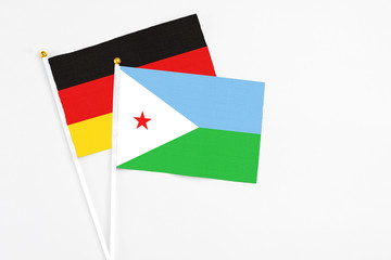 Djibouti and Germany stick flags on white background. High quality fabric, miniature national flag. Peaceful global concept.White floor for copy space.