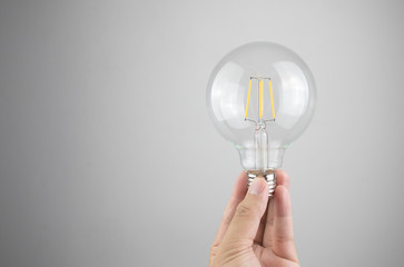 hand holding light bulb isolated gry background. 