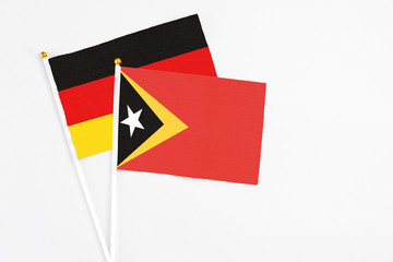 East Timor and Germany stick flags on white background. High quality fabric, miniature national flag. Peaceful global concept.White floor for copy space.