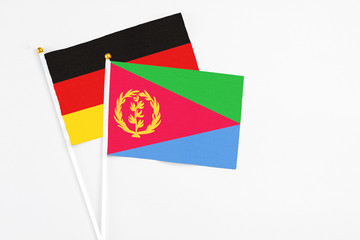 Eritrea and Germany stick flags on white background. High quality fabric, miniature national flag. Peaceful global concept.White floor for copy space.